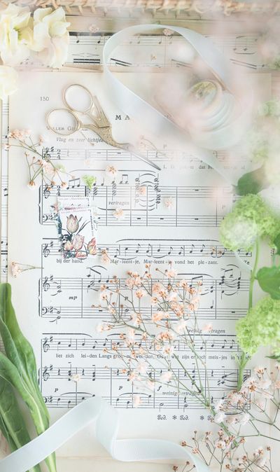Sheet music decorated with flowers, ribbon, and small golden scissors.